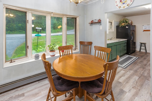 dining space with a baseboard heating unit, plenty of natural light, light wood finished floors, and crown molding