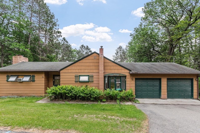 mid-century inspired home with a chimney, an attached garage, a front lawn, and driveway