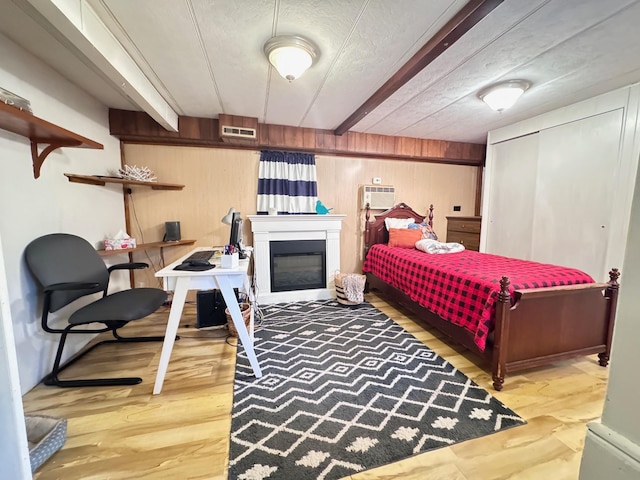 36434 145th Ave, Blueberry Twp, MN 56464 - bedroom with wooden walls, wood finished floors, beam ceiling, a wall mounted AC, and a textured ceiling