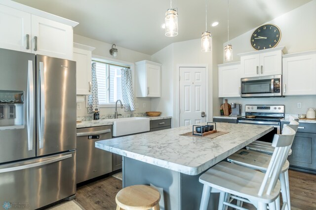 7339 21st St S, Fargo, ND 58104 - kitchen featuring appliances with stainless steel finishes, a breakfast bar area, dark wood-style floors, a center island, and white cabinets
