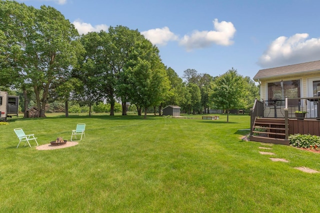 4820 Echo Ct, Faribault, MN 55021 - view of green lawn with an outdoor fire pit, a shed, and a deck