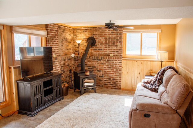36945 Delta Bay Rd, Pine River, MN 56474 - living area featuring a wood stove, a ceiling fan, a wainscoted wall, wood walls, and brick wall
