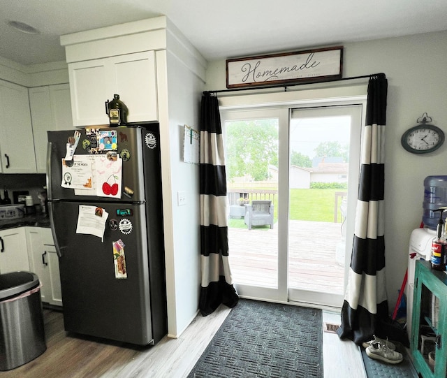 534 Main St, Perham, MN 56573 - kitchen with freestanding refrigerator, wood finished floors, white cabinets, and dark countertops