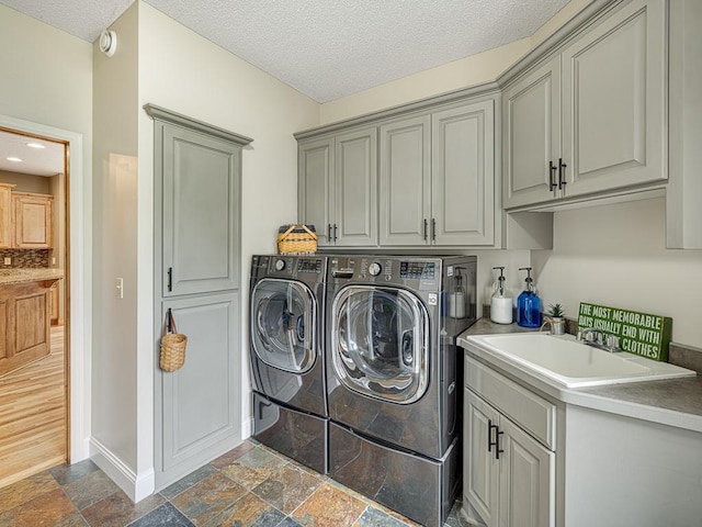 1847 140th Ln NE, Ham Lake, MN 55304 - laundry room featuring washing machine and clothes dryer, cabinet space, stone tile flooring, and a textured ceiling