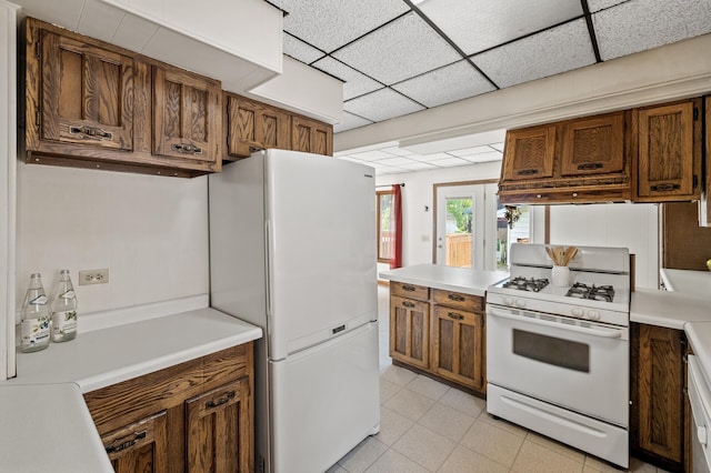 3521 26th St, Minneapolis, MN 55406 - kitchen featuring white appliances, light countertops, brown cabinetry, and a paneled ceiling