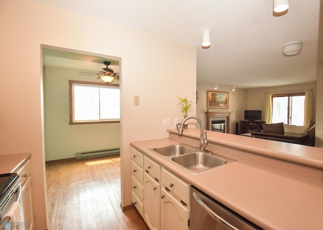 2515 25th St S Unit 303H, Fargo, ND 58103 - kitchen with a baseboard radiator, appliances with stainless steel finishes, light countertops, white cabinets, and a glass covered fireplace