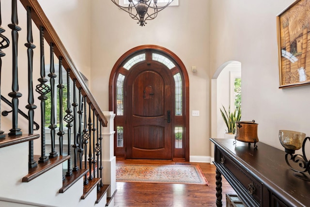 16209 Adeline Ln, Minnetonka, MN 55391 - foyer entrance with arched walkways, wood finished floors, a high ceiling, a chandelier, and stairs