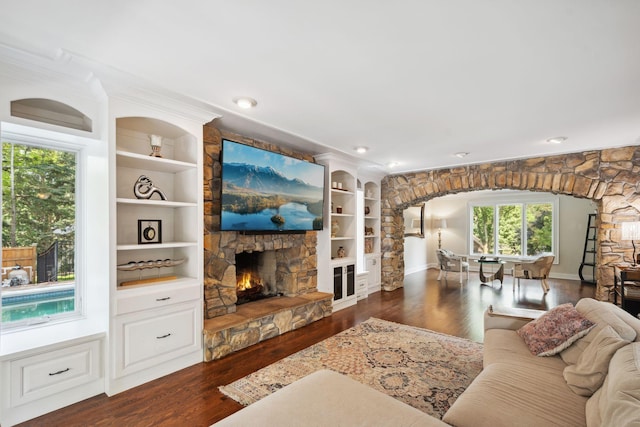 16209 Adeline Ln, Minnetonka, MN 55391 - living room featuring dark wood-style flooring, a stone fireplace, arched walkways, and built in shelves