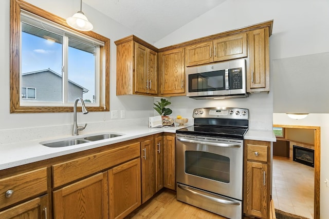 382 Tuttle Dr, Hastings, MN 55033 - kitchen with stainless steel appliances, lofted ceiling, brown cabinetry, light countertops, and decorative light fixtures