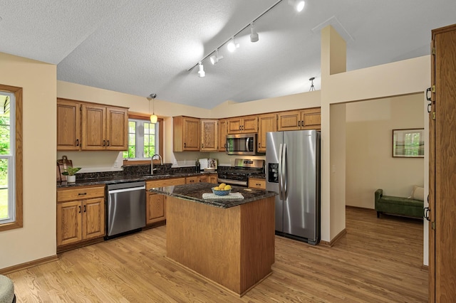 17121 Variolite St NW, Ramsey, MN 55303 - kitchen featuring appliances with stainless steel finishes, track lighting, lofted ceiling, light wood finished floors, and brown cabinetry