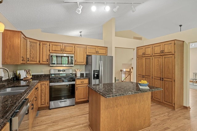 17121 Variolite St NW, Ramsey, MN 55303 - kitchen with appliances with stainless steel finishes, lofted ceiling, light wood-style flooring, dark stone counters, and a center island