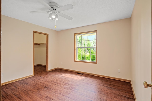 17121 Variolite St NW, Ramsey, MN 55303 - unfurnished bedroom with wood finished floors, a walk in closet, a ceiling fan, and a closet