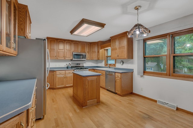 808 17th St SW, Willmar, MN 56201 - kitchen with stainless steel appliances, light wood finished floors, glass insert cabinets, a center island, and hanging light fixtures