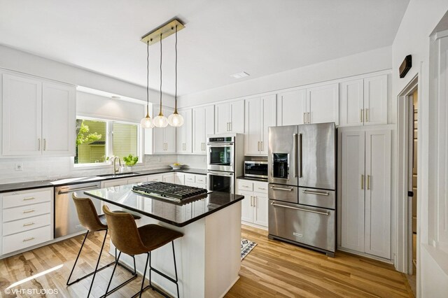 820 Vineland Ct, Chanhassen, MN 55317 - kitchen featuring appliances with stainless steel finishes, a breakfast bar area, white cabinetry, tasteful backsplash, and light wood finished floors