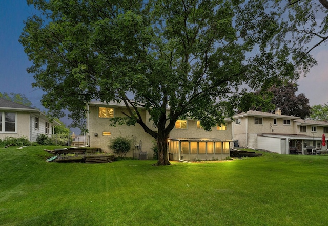 354 Edith Dr W, Saint Paul, MN 55118 - back of house at dusk featuring a yard, an attached garage, and a sunroom
