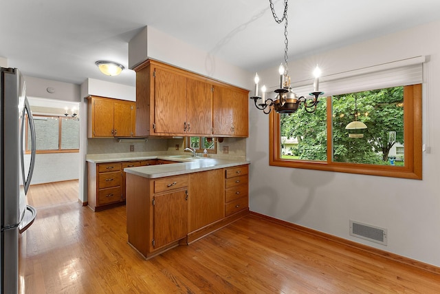 354 Edith Dr W, Saint Paul, MN 55118 - kitchen featuring freestanding refrigerator, a chandelier, a peninsula, and brown cabinetry