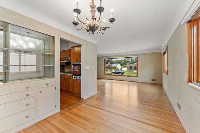 354 Edith Dr W, Saint Paul, MN 55118 - unfurnished dining area with light wood-style floors, a chandelier, and a textured wall