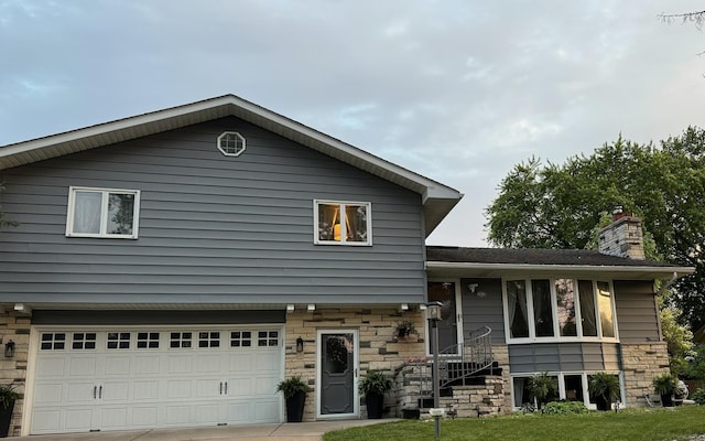 1439 7th St SW, New Brighton, MN 55112 - tri-level home with stone siding, an attached garage, a chimney, and driveway