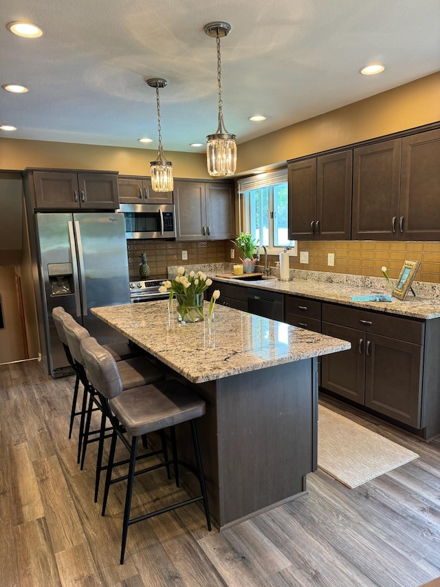 1439 7th St SW, New Brighton, MN 55112 - kitchen with stainless steel appliances, a center island, a kitchen bar, light stone countertops, and recessed lighting