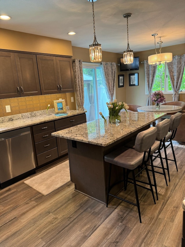 1439 7th St SW, New Brighton, MN 55112 - kitchen featuring light wood-style flooring, a breakfast bar area, dark brown cabinets, dishwasher, and tasteful backsplash