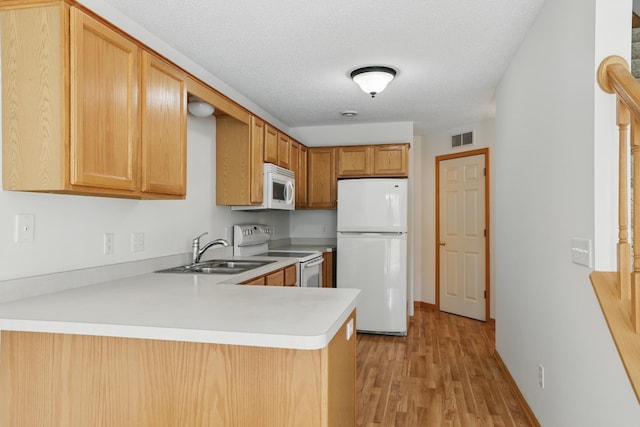 8741 Quarry Ridge Ln Unit H, Woodbury, MN 55125 - kitchen with white appliances, a peninsula, light wood-style floors, light countertops, and a textured ceiling