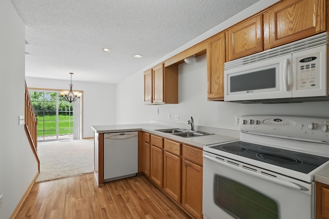 8741 Quarry Ridge Ln Unit H, Woodbury, MN 55125 - kitchen with white appliances, light wood-style flooring, a chandelier, light countertops, and a peninsula