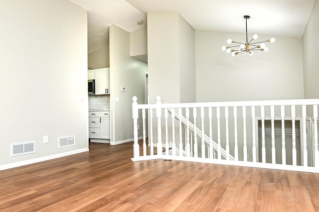 1527 Harvest Ln, Shakopee, MN 55379 - spare room featuring vaulted ceiling, a chandelier, and wood finished floors
