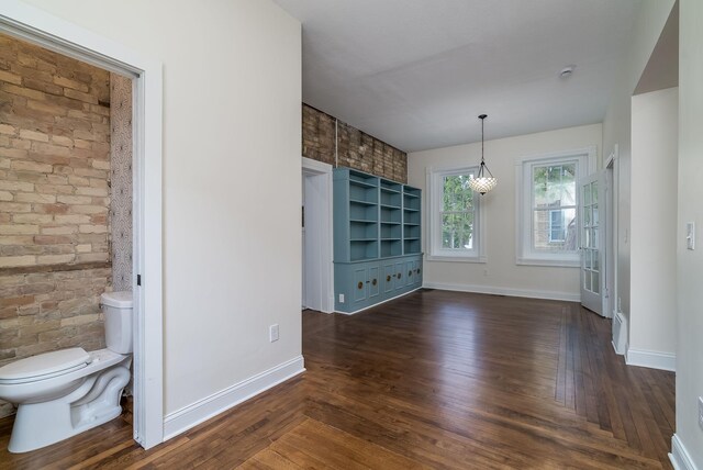 121 Hickory St, Chaska, MN 55318 - unfurnished dining area featuring brick wall, dark wood-style floors, and an accent wall