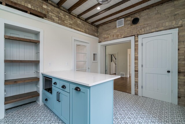 121 Hickory St, Chaska, MN 55318 - kitchen featuring blue cabinets, a peninsula, beamed ceiling, light countertops, and light flooring