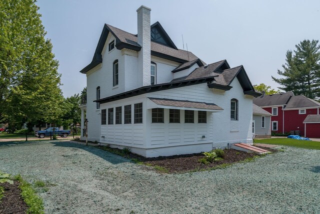 121 Hickory St, Chaska, MN 55318 - view of property exterior featuring a chimney, a shingled roof, and brick siding