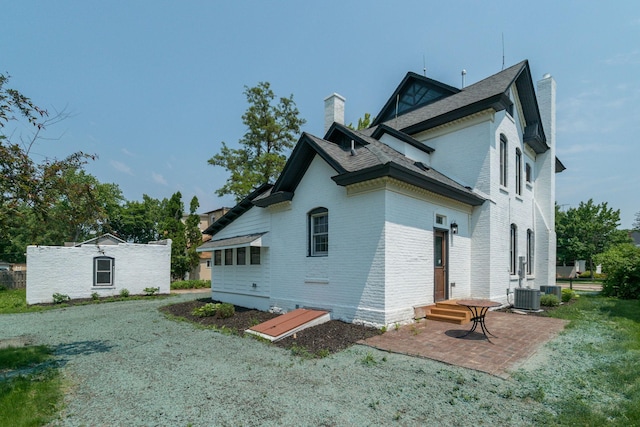 121 Hickory St, Chaska, MN 55318 - view of property exterior featuring a chimney, brick siding, a patio, and a shingled roof