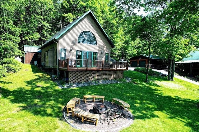 W6741 Lakewood Blvd, Dewey Twp, WI 54848 - rear view of property featuring an outdoor fire pit, a deck, an outbuilding, and a yard