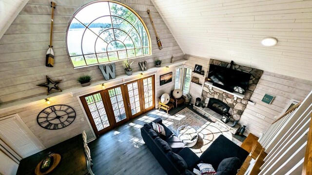 W6741 Lakewood Blvd, Dewey Twp, WI 54848 - living area featuring wooden walls, lofted ceiling, dark wood finished floors, a stone fireplace, and french doors
