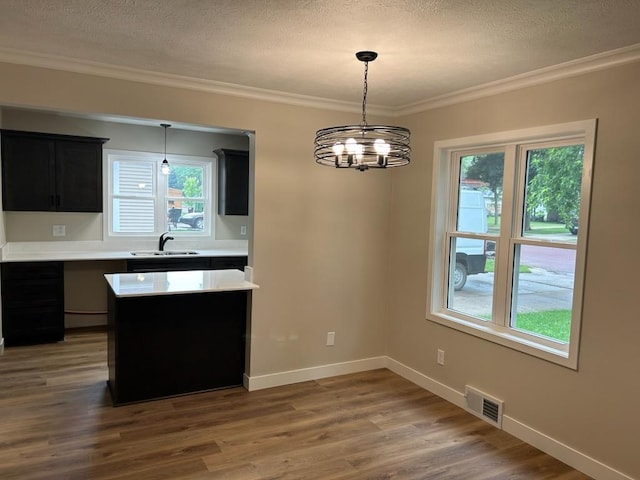 206 3rd St, Minneota, MN 56264 - kitchen featuring light countertops, ornamental molding, wood finished floors, dark cabinetry, and a chandelier