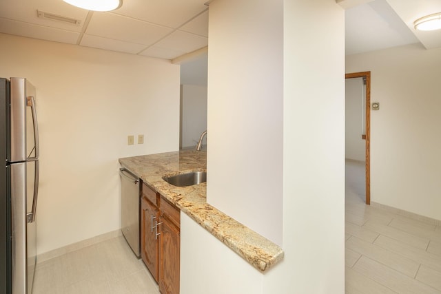 220 Broadway Ave S Unit 1221, Rochester, MN 55904 - kitchen featuring appliances with stainless steel finishes, brown cabinetry, light stone countertops, and a drop ceiling