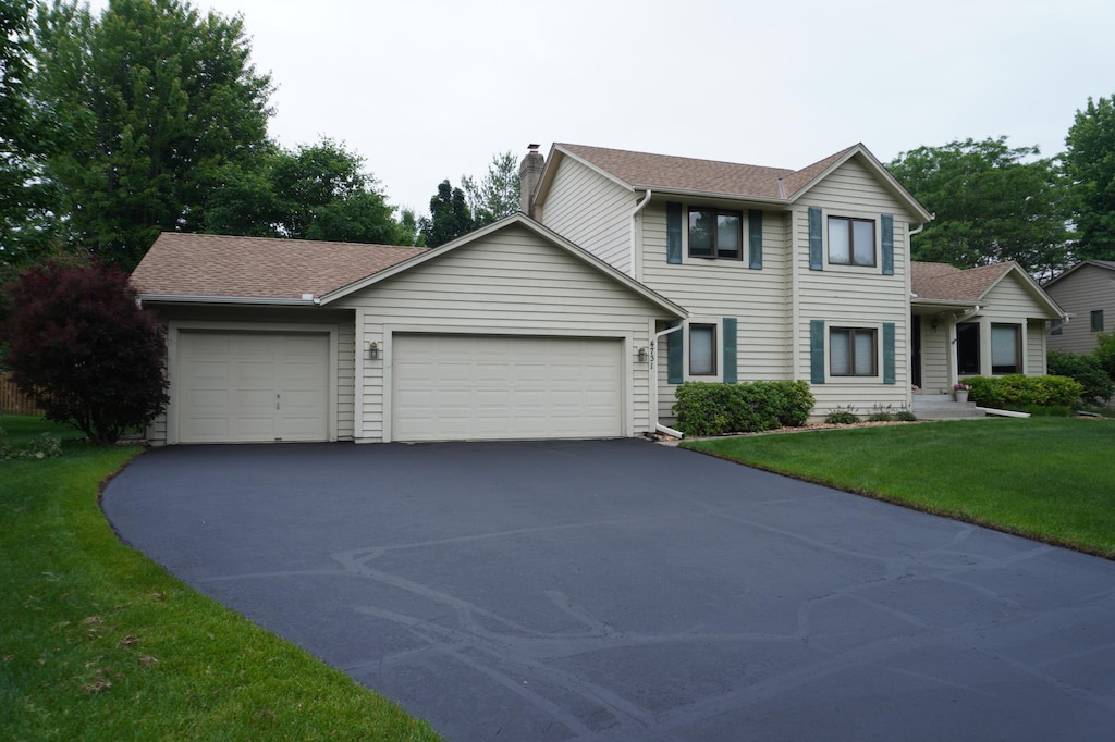 4731 Hazeltine Ln, Eagan, MN 55123 - traditional home featuring driveway, a garage, a chimney, a front lawn, and roof with shingles