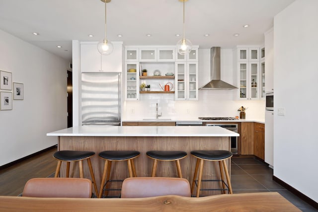 201 11th St Unit 530, Minneapolis, MN 55403 - kitchen featuring appliances with stainless steel finishes, wall chimney range hood, tasteful backsplash, a breakfast bar area, and light countertops