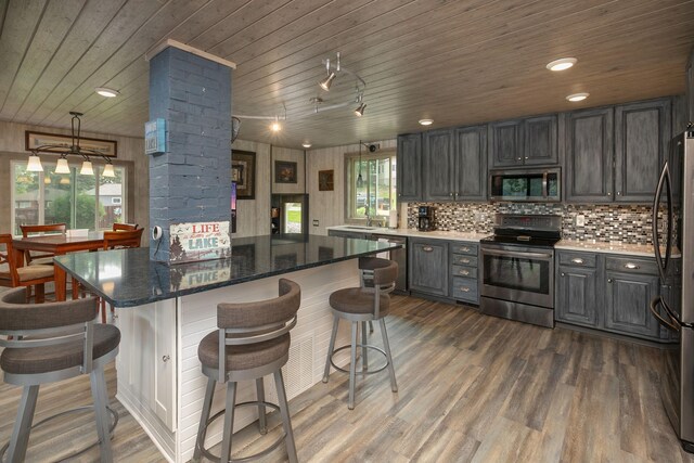 40536 Ryans Bay Rd, Zumbro Twp, MN 55991 - kitchen with stainless steel appliances, wooden ceiling, ornate columns, dark wood-style flooring, and a kitchen breakfast bar