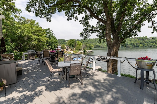 40536 Ryans Bay Rd, Zumbro Twp, MN 55991 - wooden deck featuring outdoor dining space, a water view, and a forest view
