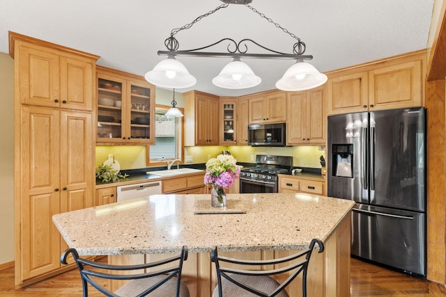 13048 Jay St NW, Coon Rapids, MN 55448 - kitchen featuring appliances with stainless steel finishes, a center island, wood finished floors, and light stone countertops