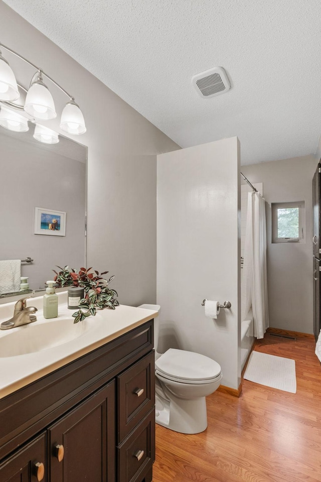 13048 Jay St NW, Coon Rapids, MN 55448 - bathroom featuring vanity, wood finished floors, a textured ceiling, and shower / bath combo with shower curtain