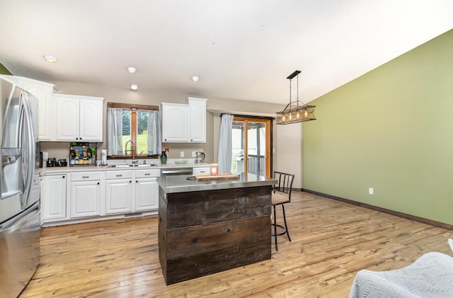 204 Sidney St E, Morristown, MN 55052 - kitchen featuring stainless steel refrigerator with ice dispenser, white cabinetry, pendant lighting, light wood finished floors, and a center island