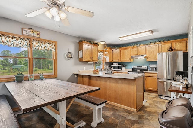 2796 269th Ave NE, Isanti, MN 55040 - kitchen with stainless steel appliances, under cabinet range hood, a peninsula, light countertops, and stone finish flooring