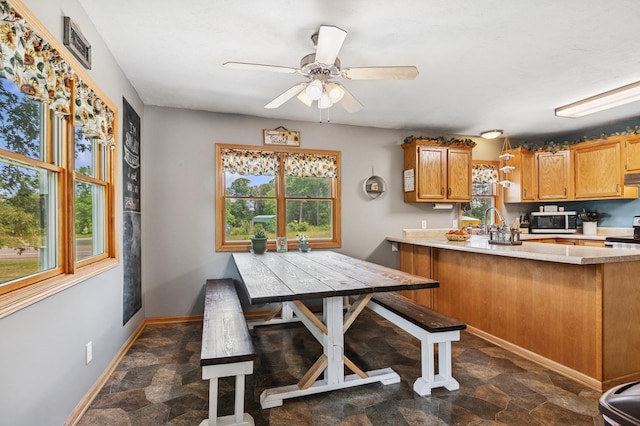 2796 269th Ave NE, Isanti, MN 55040 - kitchen featuring appliances with stainless steel finishes, stone finish flooring, a peninsula, light countertops, and ceiling fan