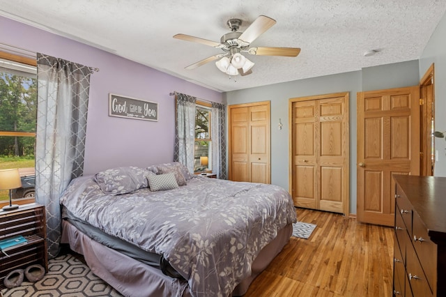 2796 269th Ave NE, Isanti, MN 55040 - bedroom featuring two closets, light wood-type flooring, a ceiling fan, and a textured ceiling