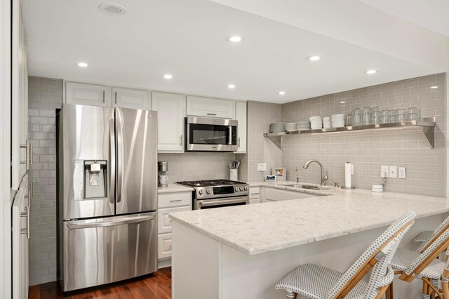 5713 Duncan Ln, Edina, MN 55436 - kitchen featuring appliances with stainless steel finishes, a peninsula, backsplash, open shelves, and white cabinets