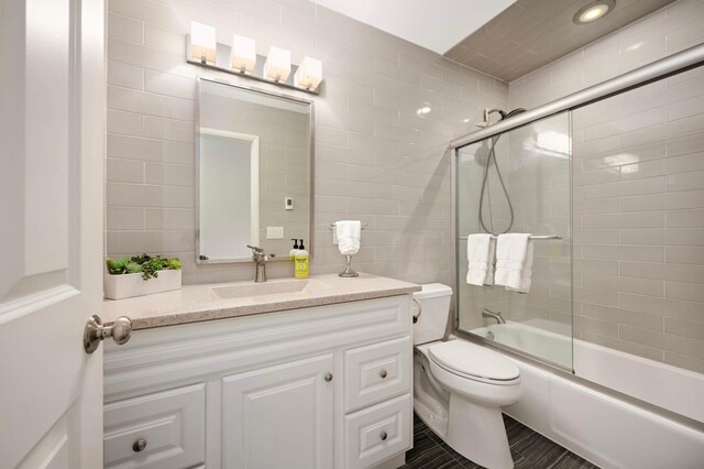 5713 Duncan Ln, Edina, MN 55436 - bathroom featuring vanity, combined bath / shower with glass door, and tile walls