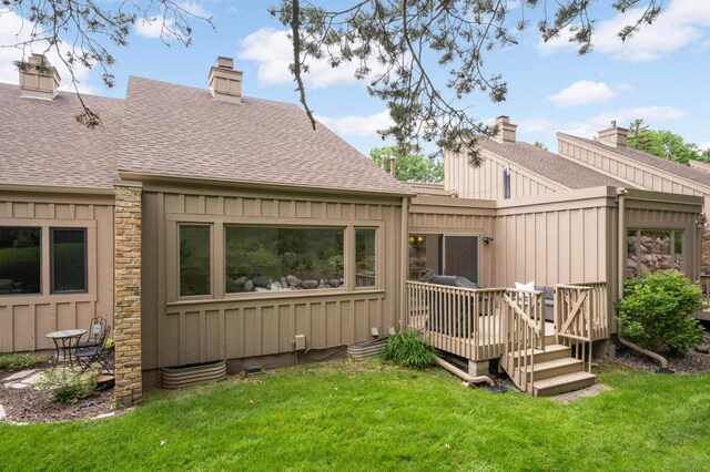 5713 Duncan Ln, Edina, MN 55436 - back of house featuring a shingled roof, a wooden deck, a chimney, and a lawn