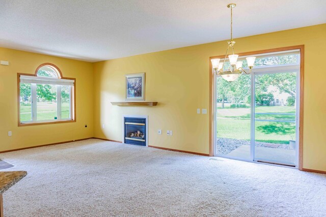 1152 Crystal Pl W, Chaska, MN 55318 - unfurnished living room with carpet, a glass covered fireplace, a chandelier, and a textured ceiling