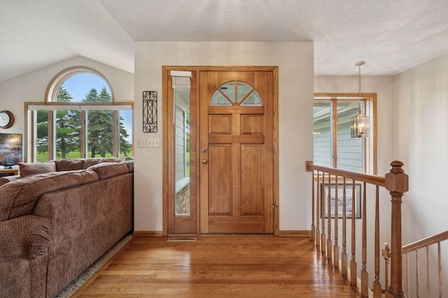 2771 County Line Ave, Osceola, WI 54020 - foyer with wood finished floors, a chandelier, a textured ceiling, and vaulted ceiling